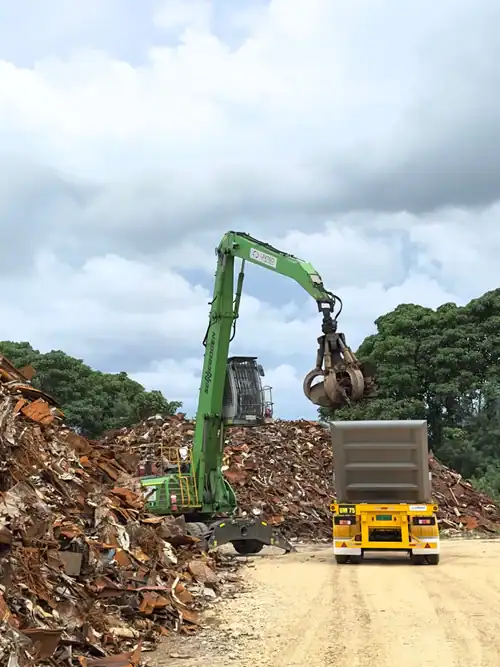 Heavy-duty scrap metal grabber in action at industrial site.