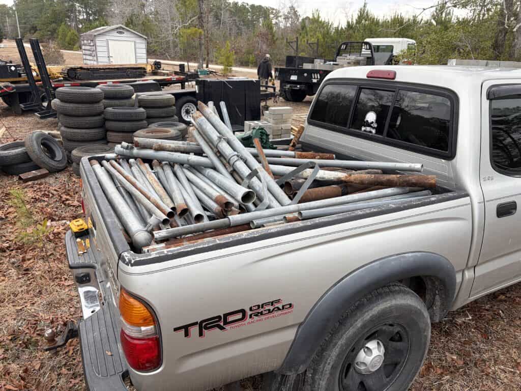 Metal scrap and discarded pipes in a truck bed at a scrap yard.