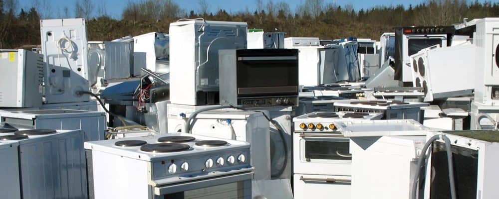 Pile of discarded white appliances and metal scrap for recycling.