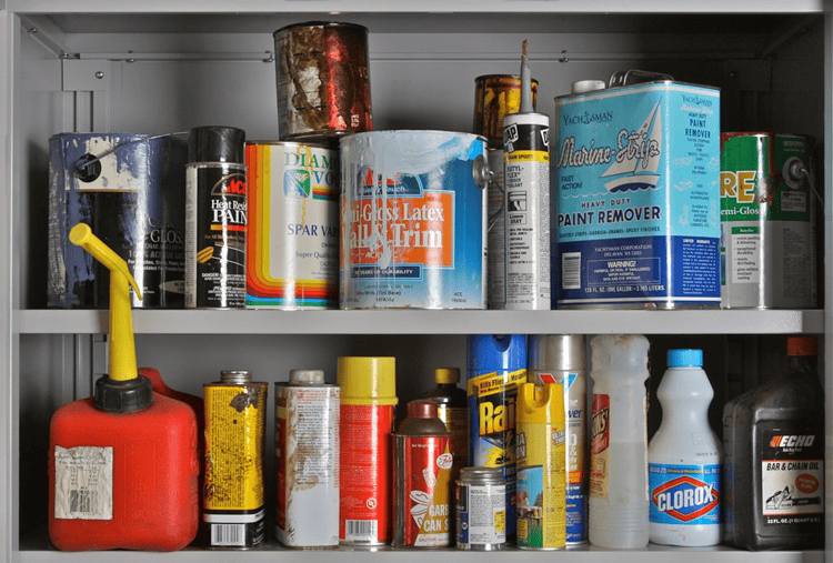 Paint and chemical cans on a storage shelf for construction and renovation projects.