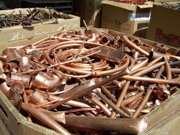 Copper scrap metal pile with pipes and tubing for recycling.