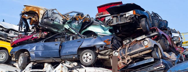 Pile of crushed and damaged vehicles ready for scrap metal recycling.