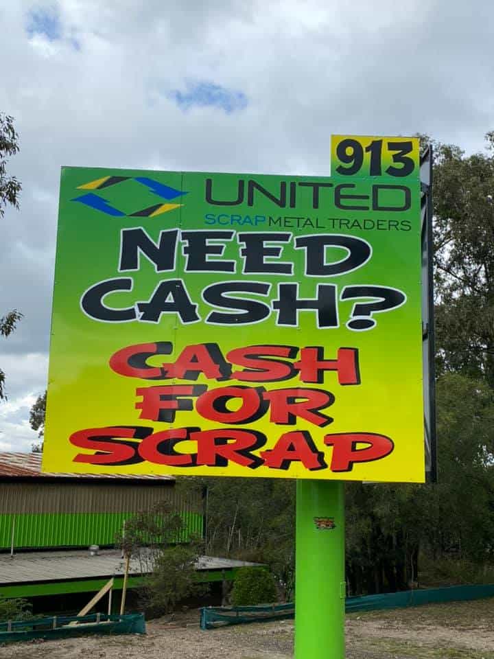 Scrap metal recycling sign offering cash for scrap metal in green and yellow colors.